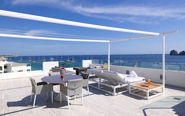 a patio with a table and chairs on a deck overlooking the ocean