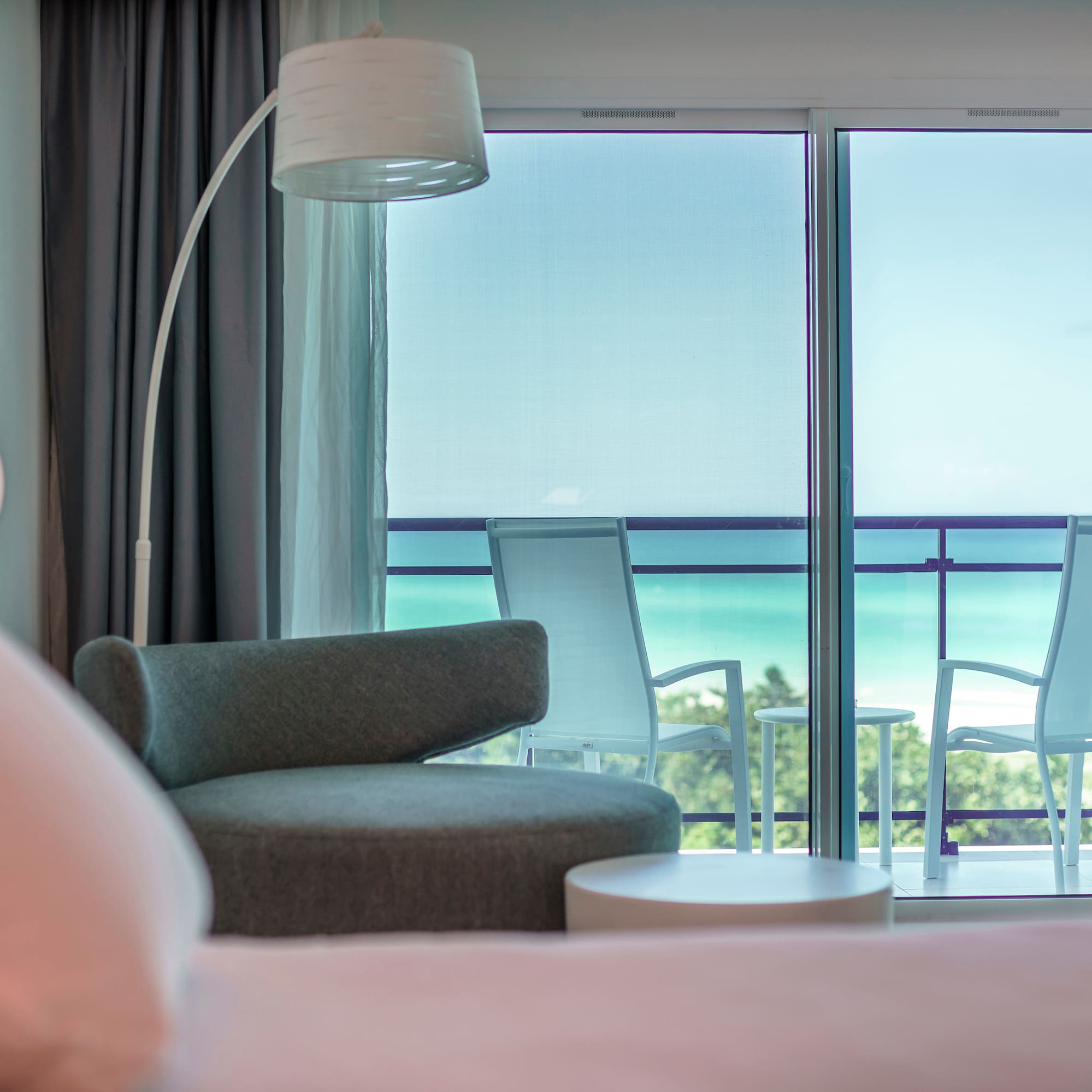 a room with a bed and chairs and a balcony