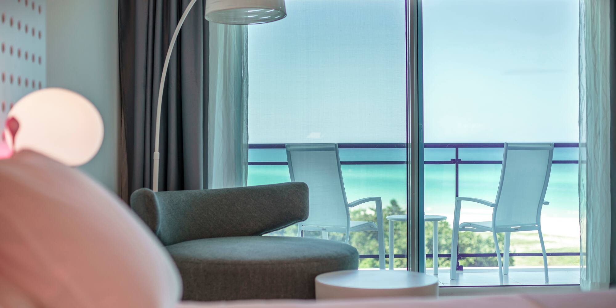 a room with a bed and chairs and a balcony