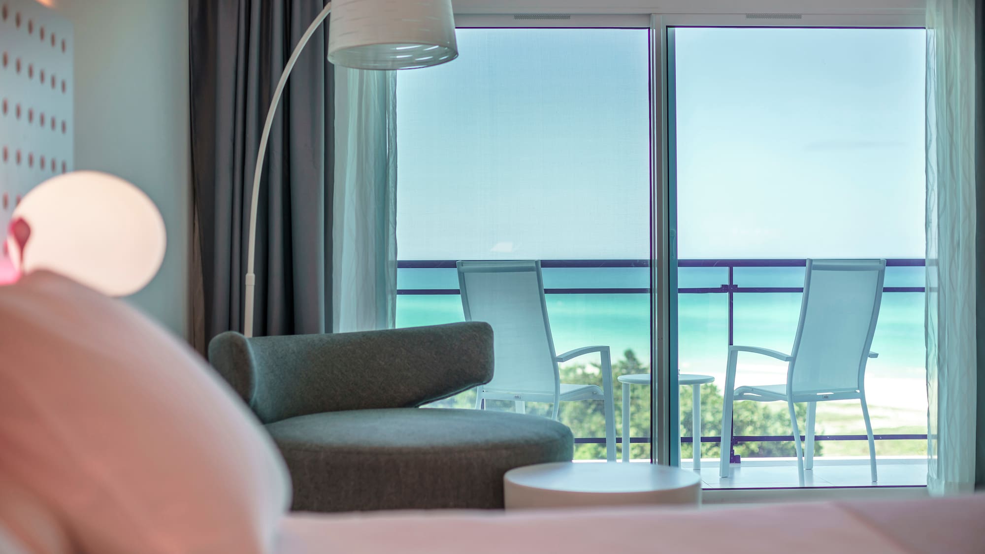 a room with a bed and chairs and a balcony