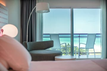 a room with a bed and chairs and a balcony
