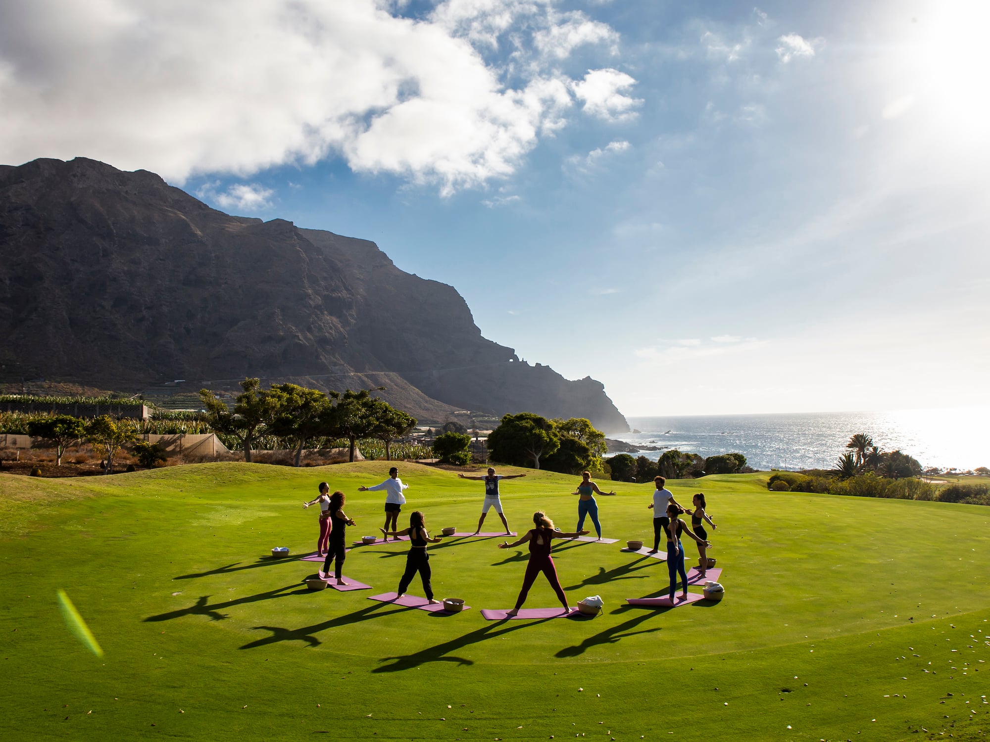 a group of people doing yoga on a grassy field