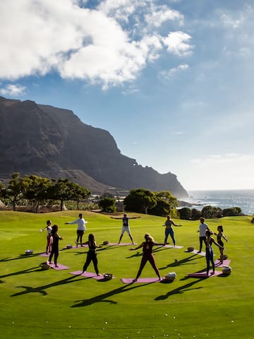a group of people doing yoga on a grassy field