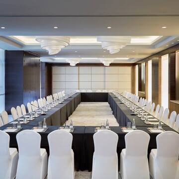 a long rectangular table with white chairs and black tablecloths