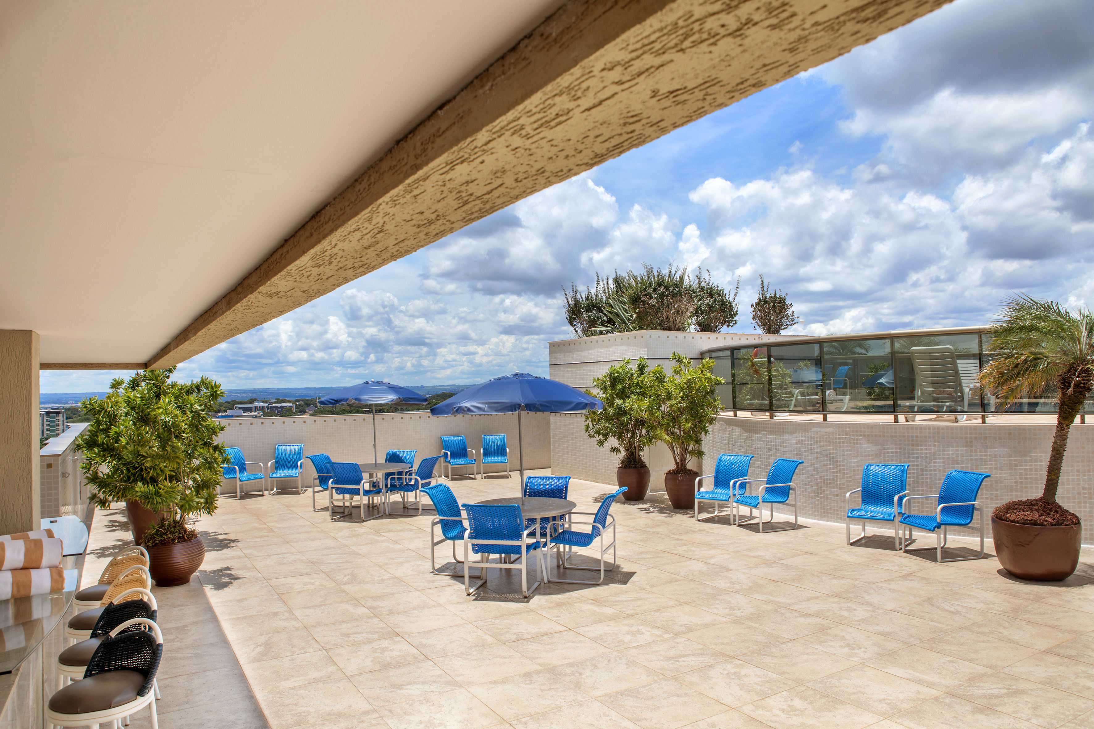 Rooftop terrace with blue patio furniture, umbrellas, and city skyline view.