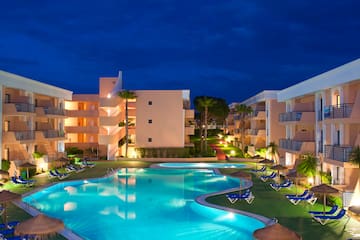 a pool with lounge chairs and a building with a dark sky