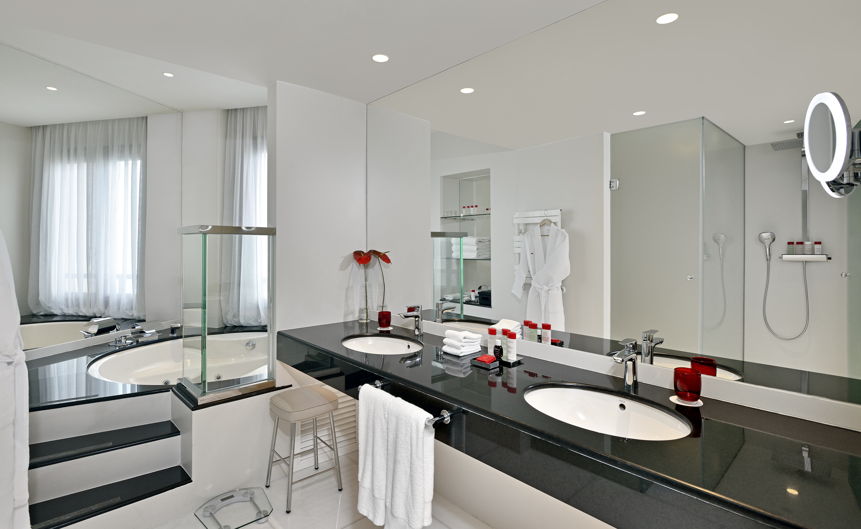 Modern hotel bathroom with double vanity, soaking tub, and glass shower.