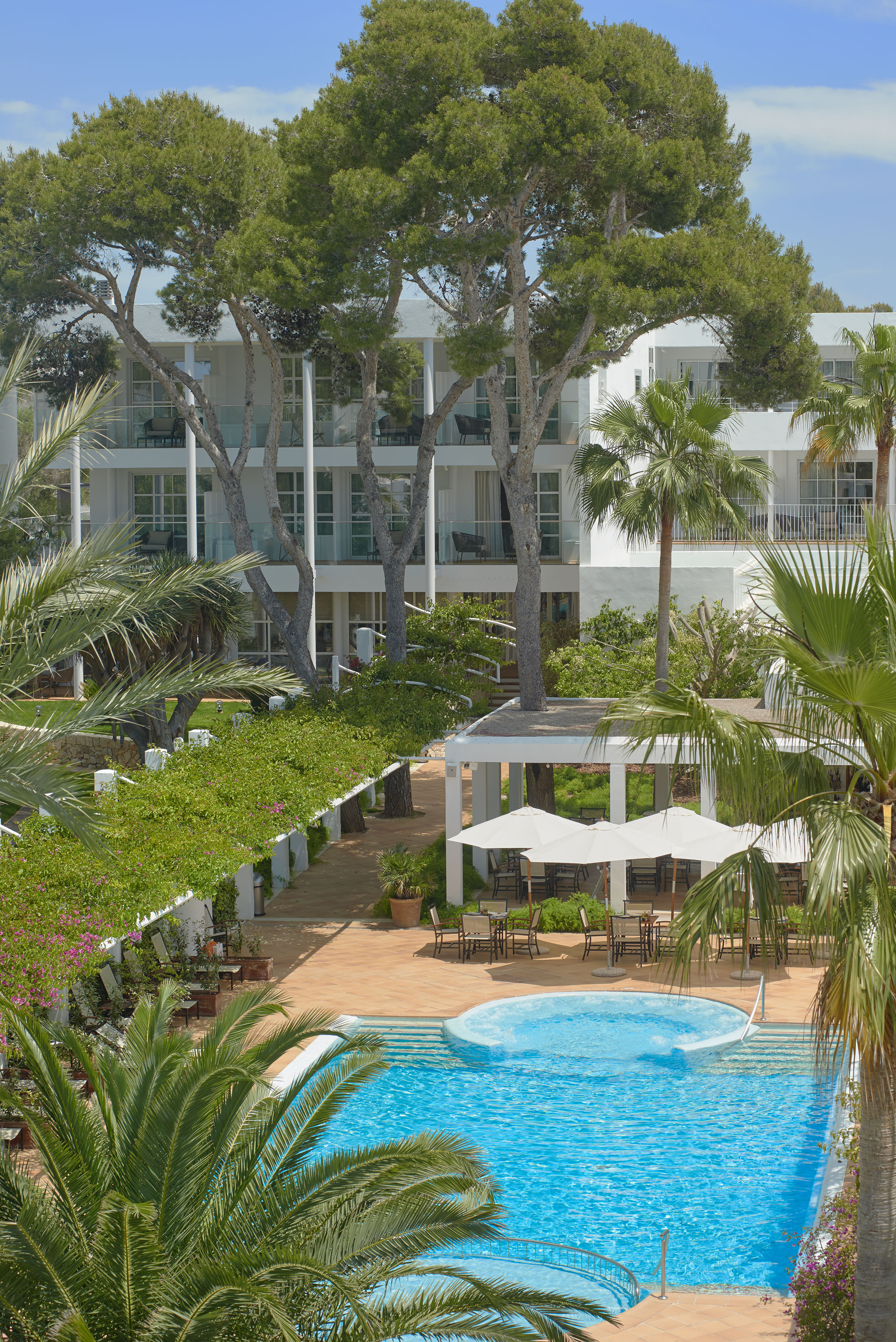 a pool with umbrellas and a building with trees
