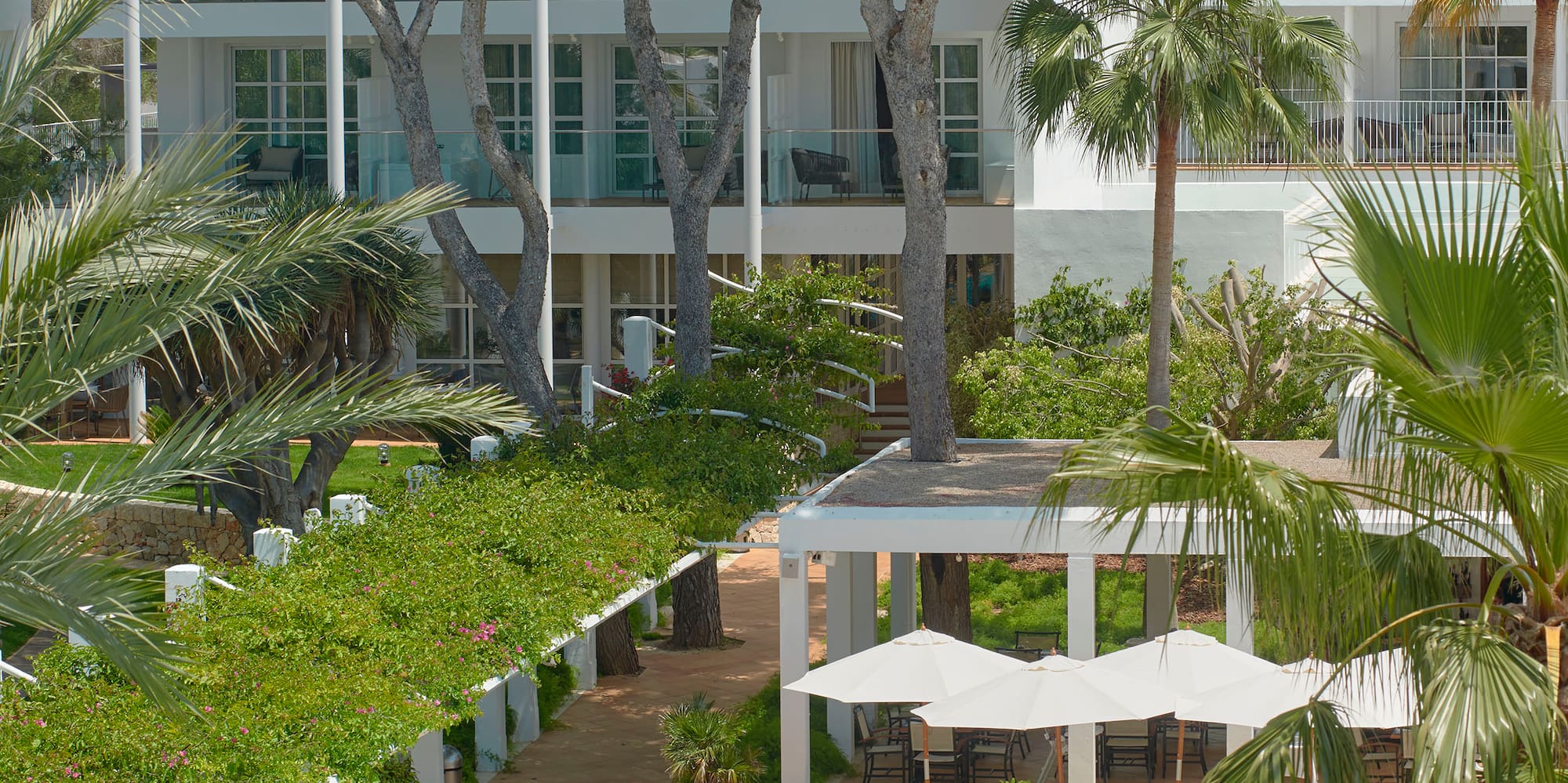 a pool with umbrellas and a building with trees