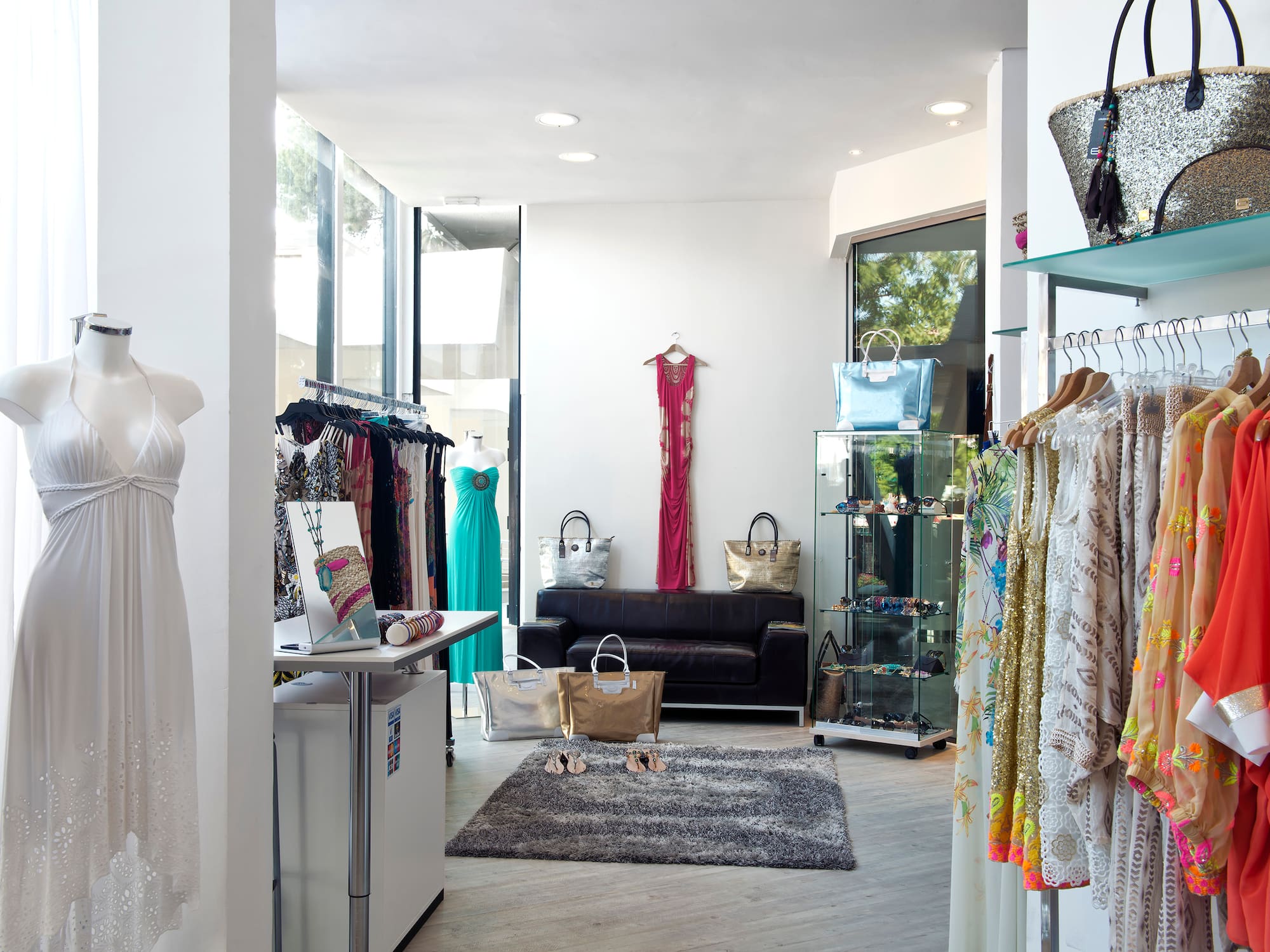 A room filled with different clothes hanging on racks and a rug on the floor.