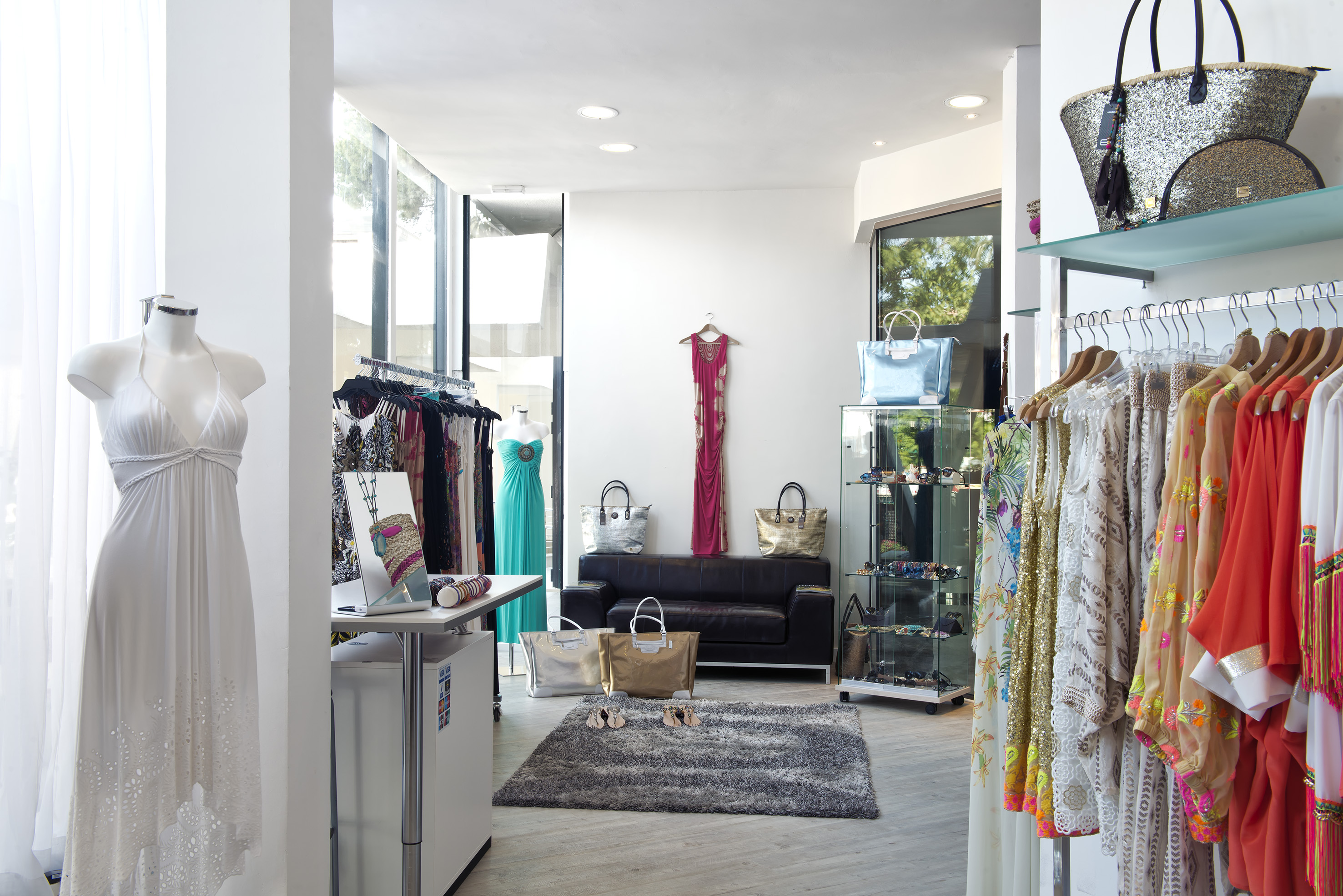 A room filled with different clothes hanging on racks and a rug on the floor.