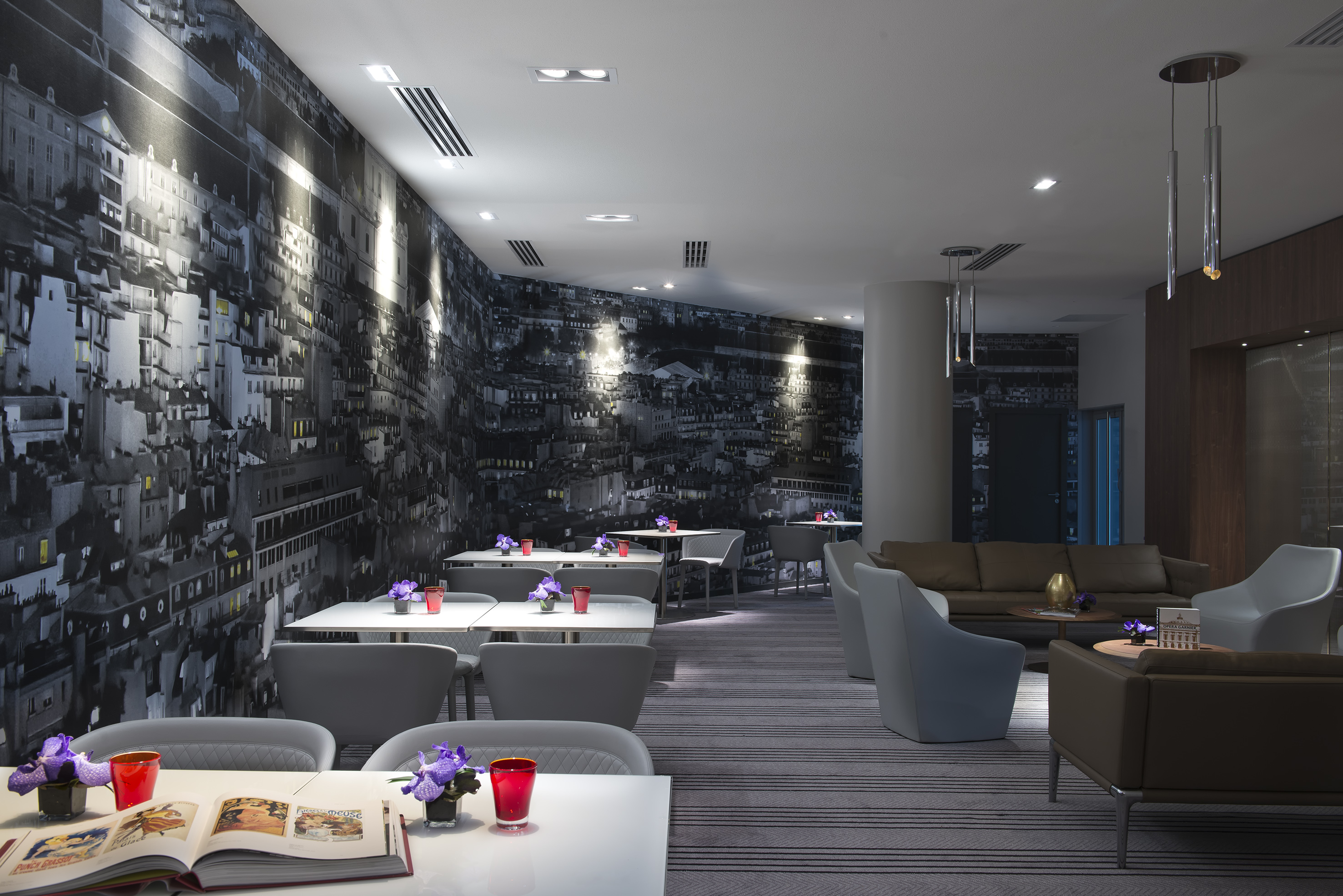 Modern cafe lounge interior with city mural wallpaper and dining tables.