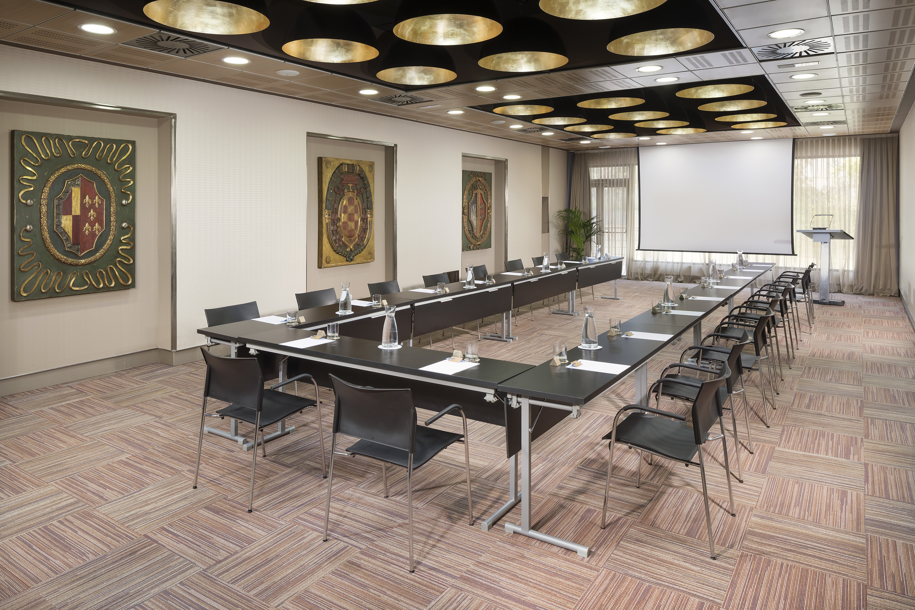 Corporate boardroom with U-shaped table setup and projector screen.