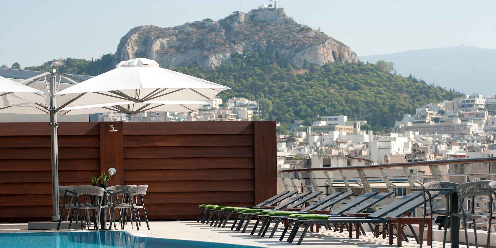 a pool with chairs and umbrellas by a building