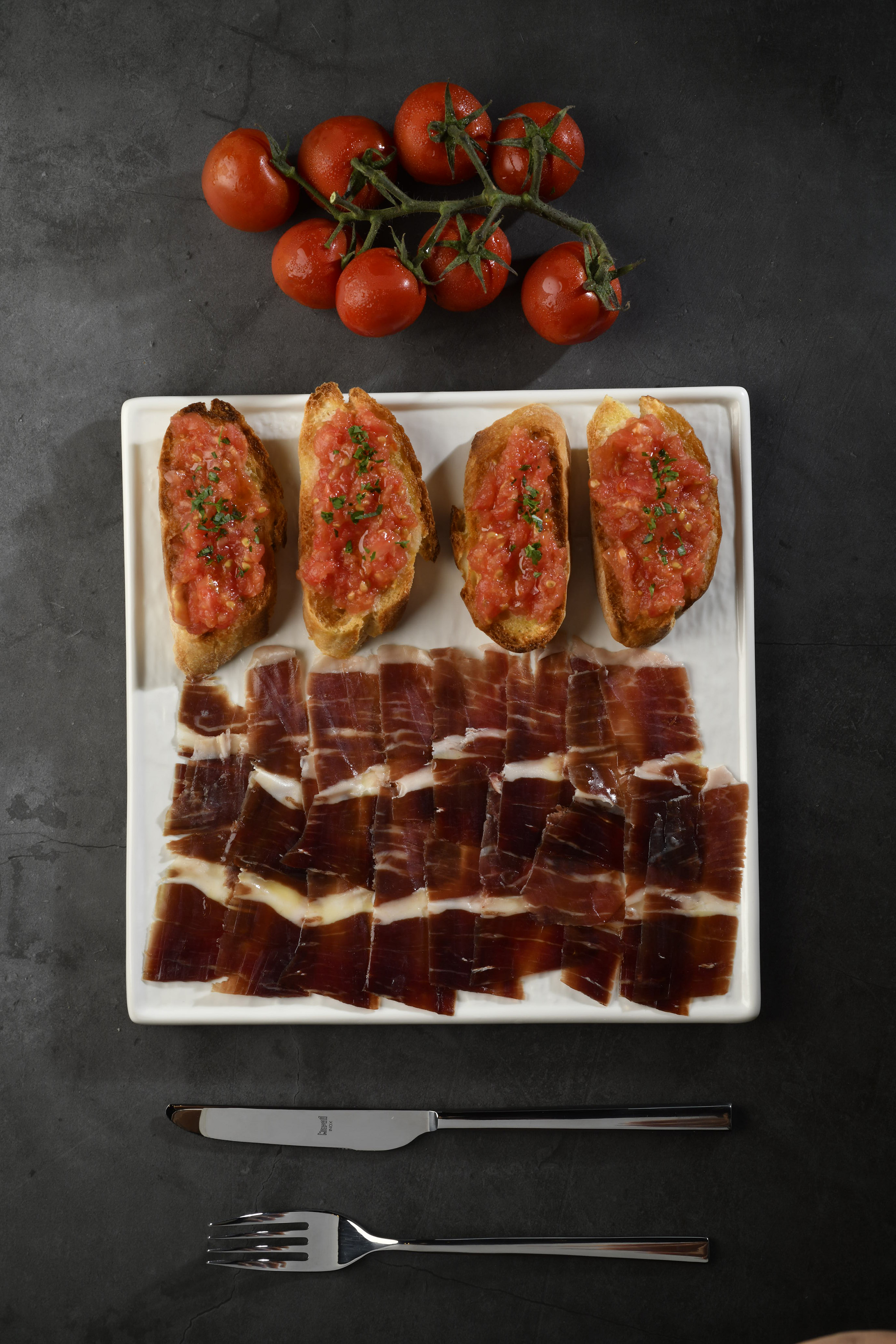 Spanish tapas: jamón, pan con tomate, and fresh tomatoes.