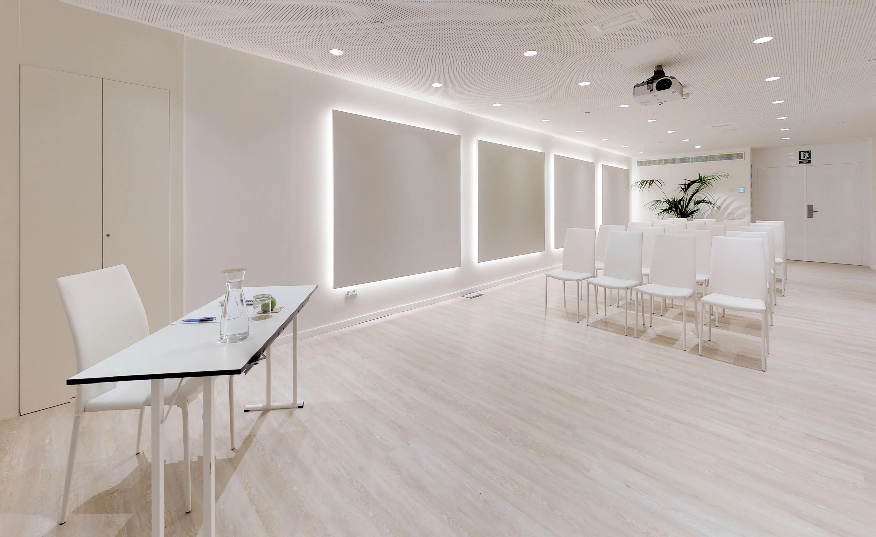 Modern conference room with white chairs, projector, and light wood floor.