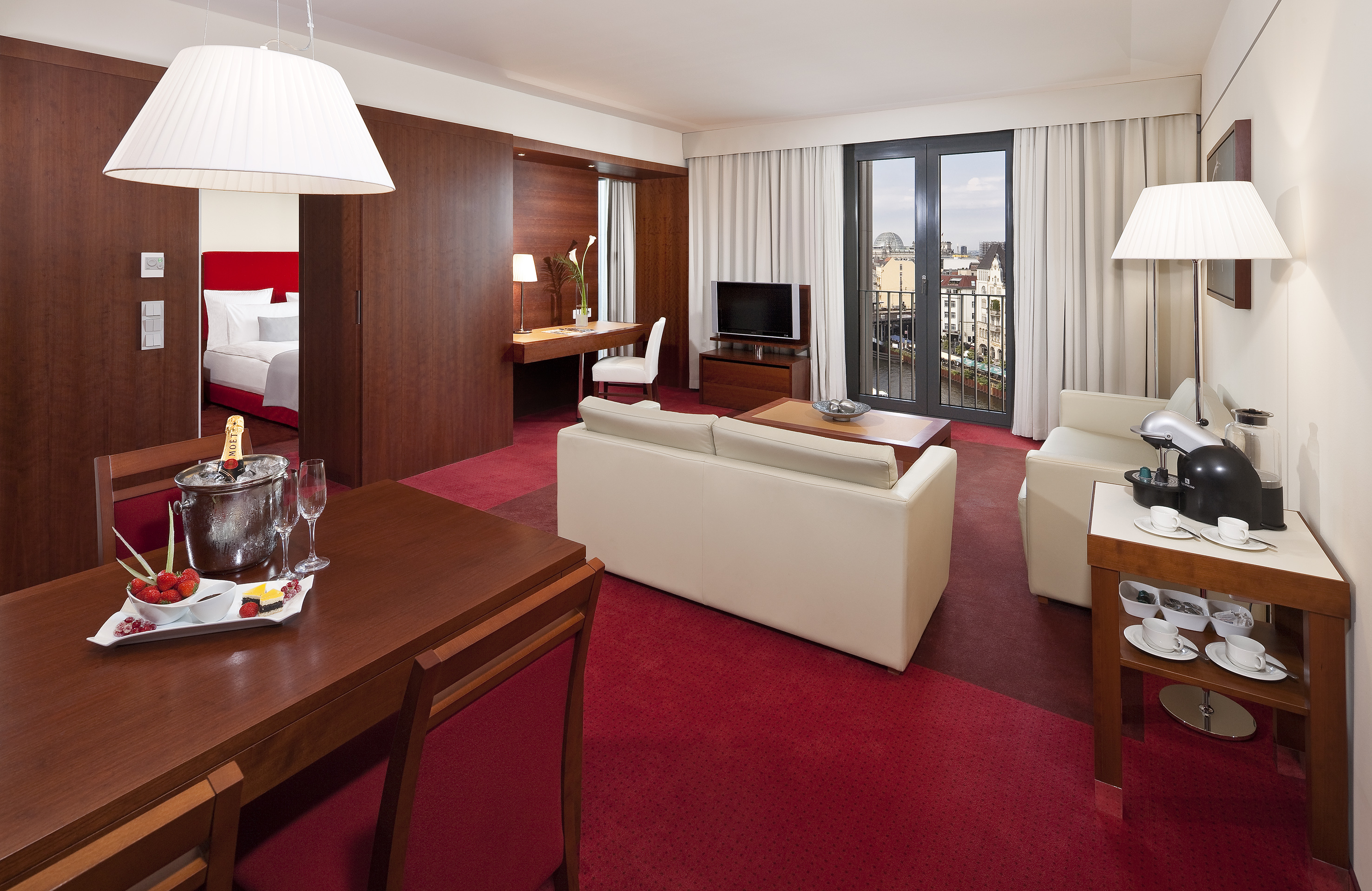 Hotel suite living room, dining, champagne, and balcony city view.