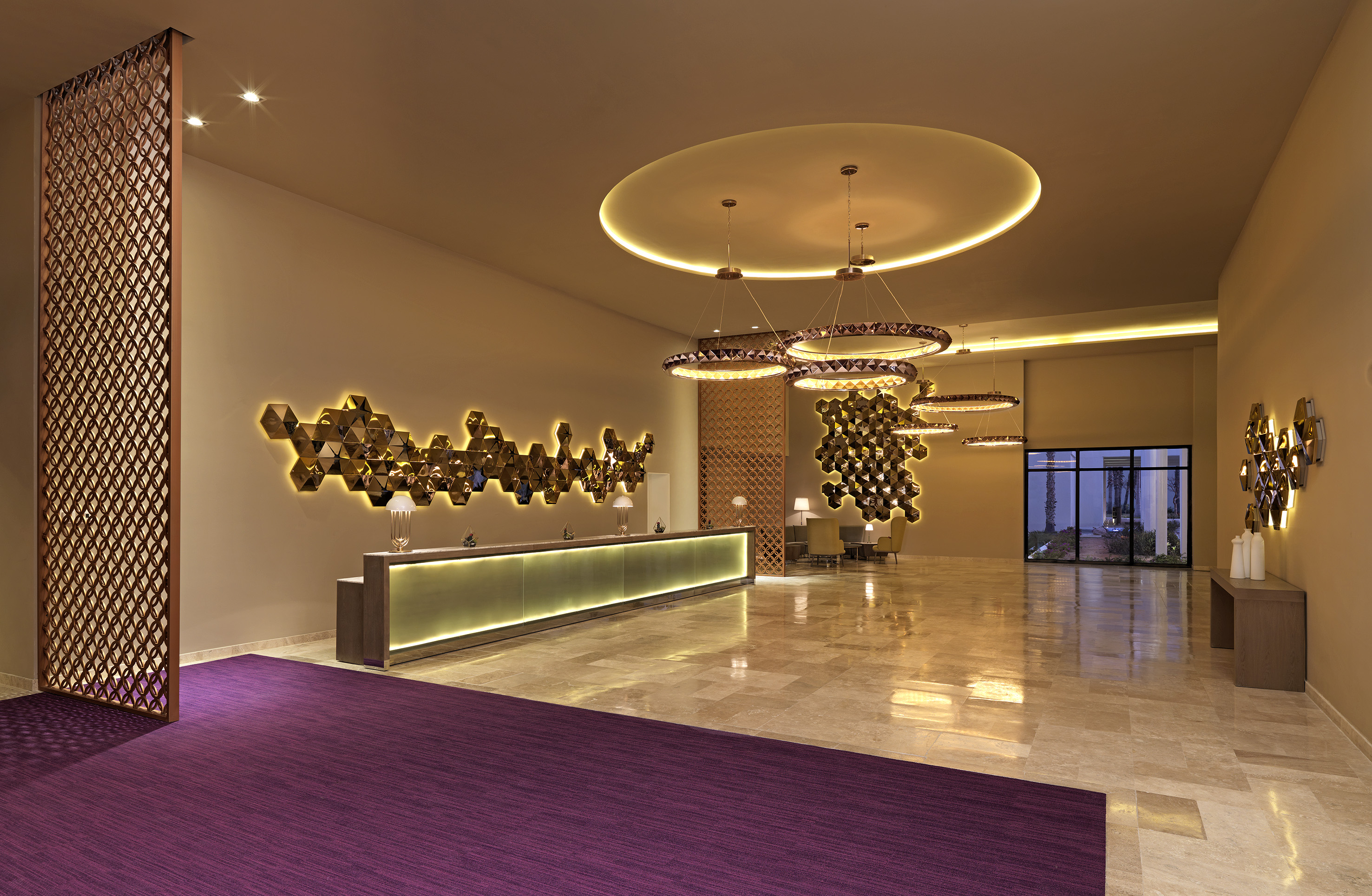 Luxurious hotel lobby with glowing reception desk and backlit hexagonal wall art.