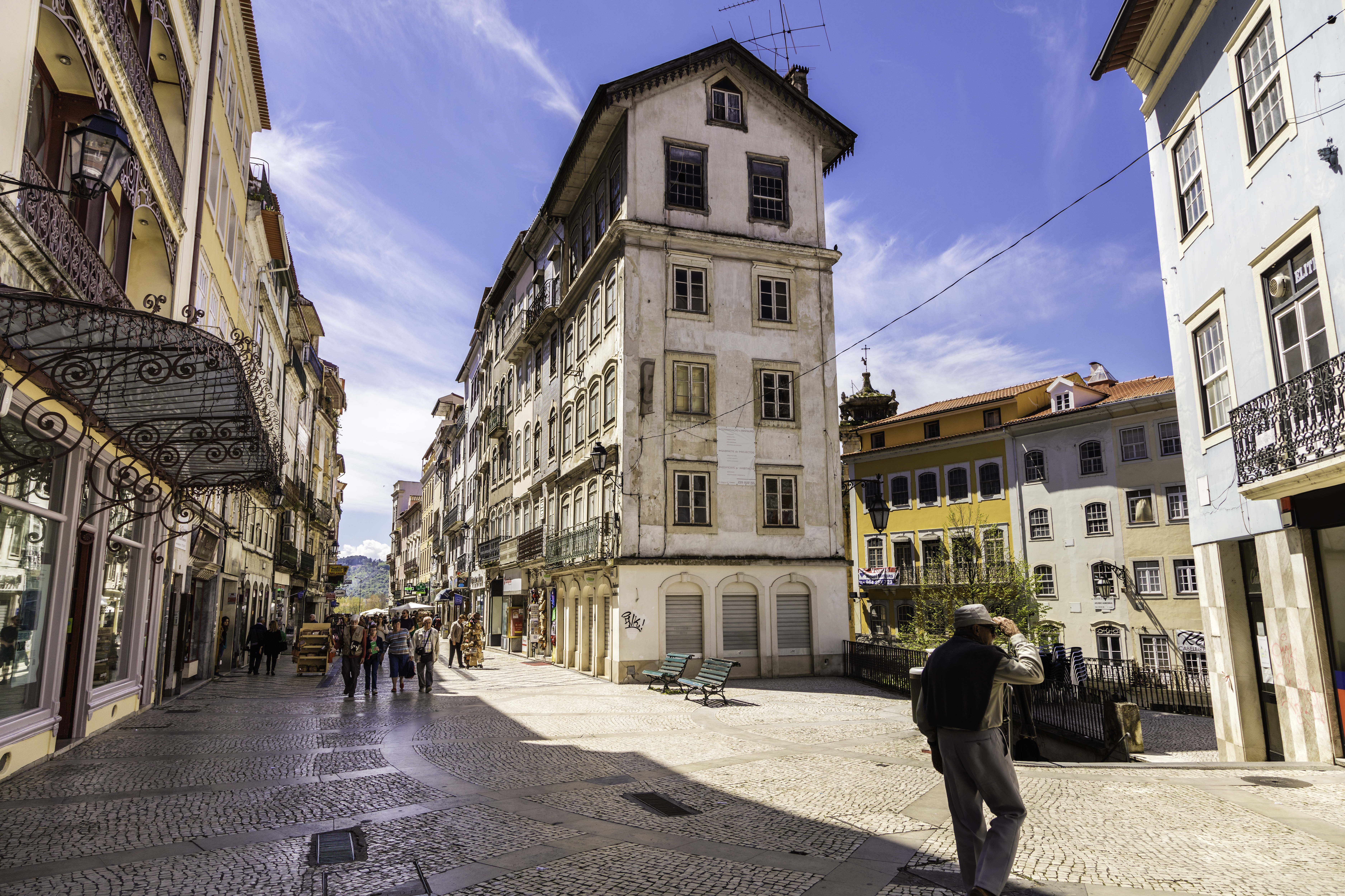 Historic old town street with tall buildings, cobblestones, and people walking.