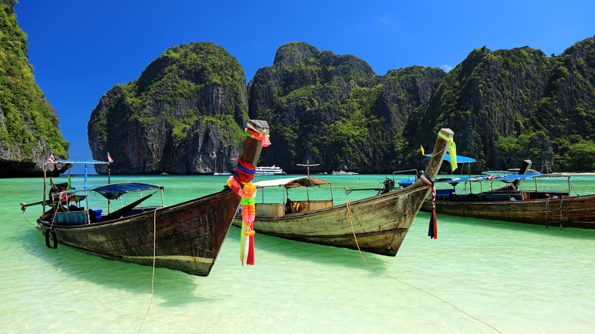 boats in the water with mountains in the background with Phi Phi Islands in the background