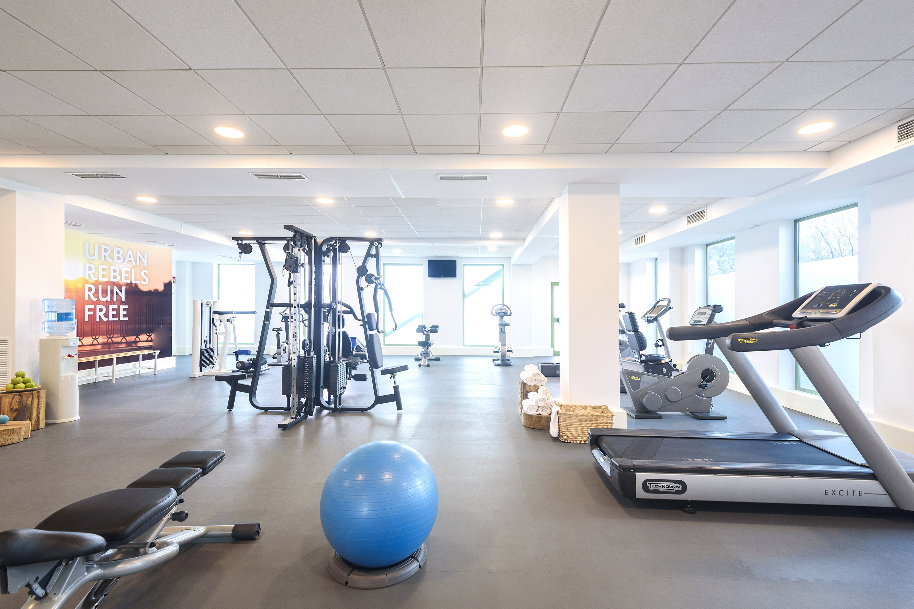 Modern gym with treadmill, weight machines, exercise ball, and fitness equipment.