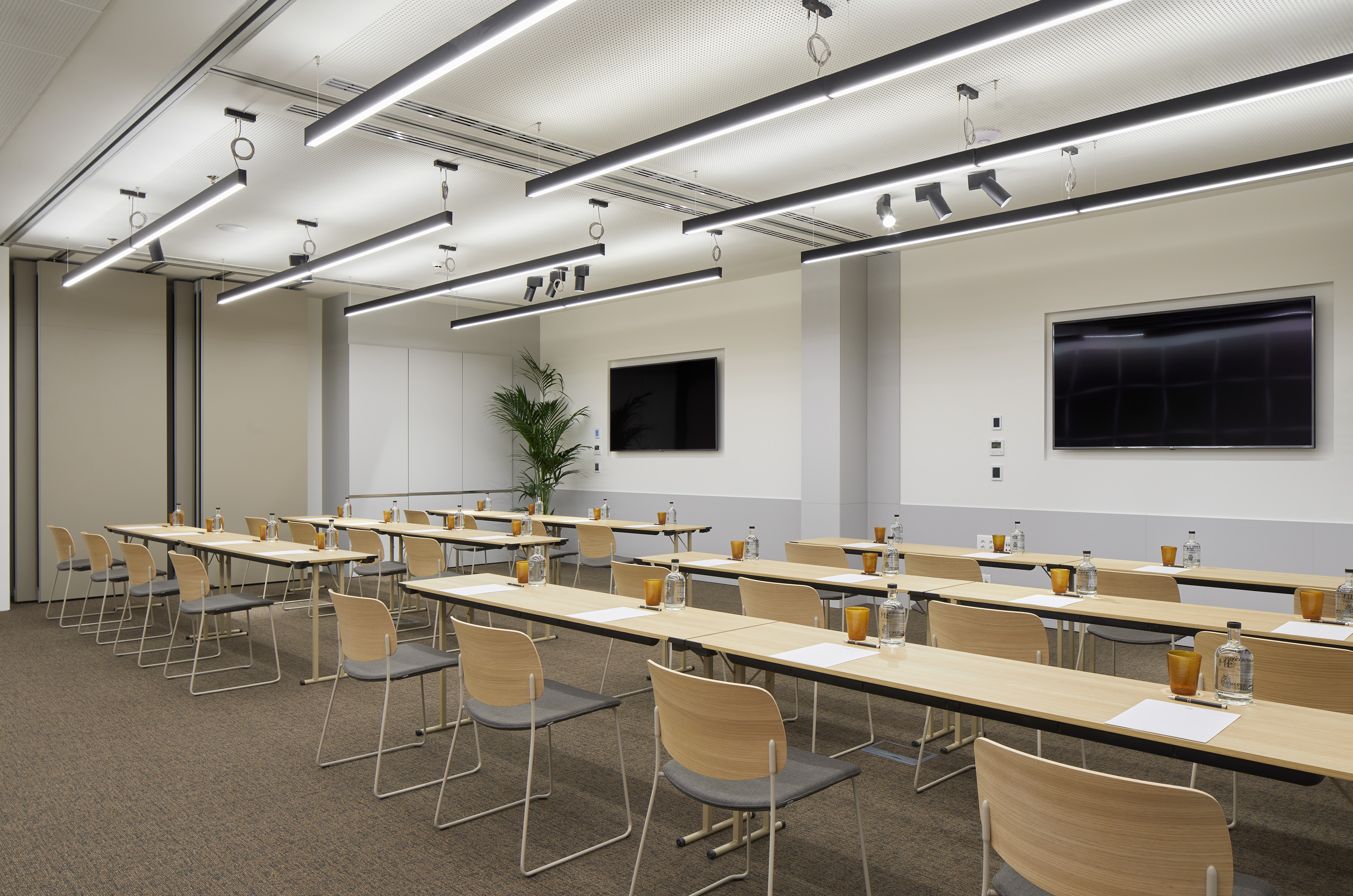 Contemporary meeting room with tables, chairs, and large wall screens.