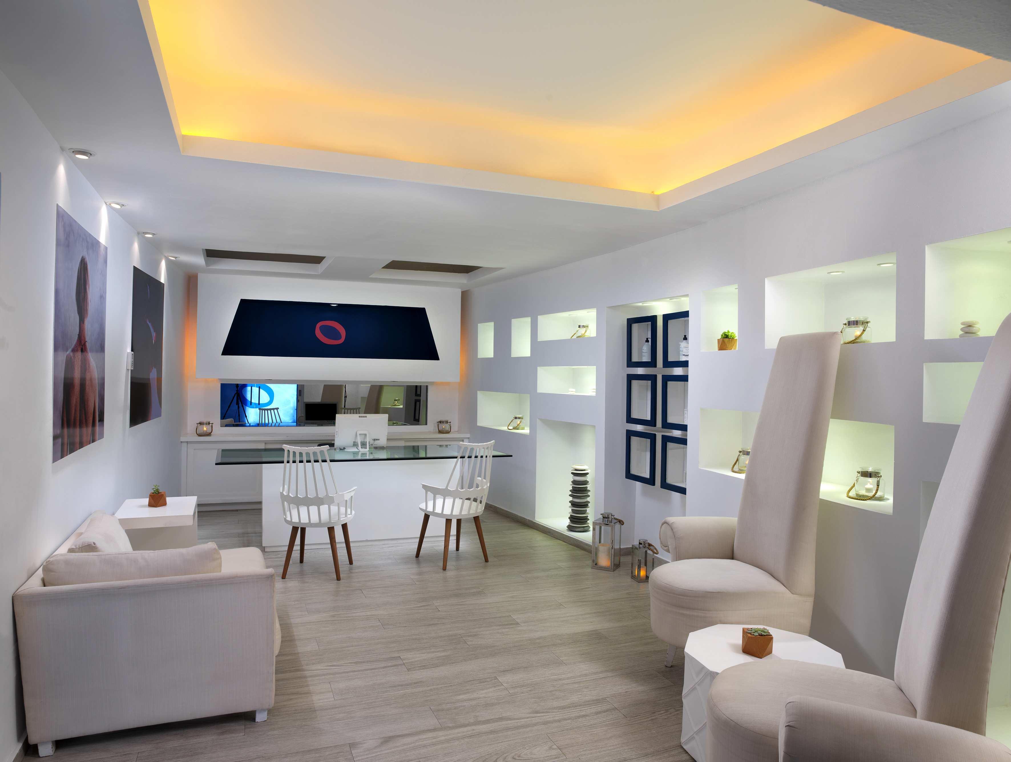Modern minimalist reception area with white furniture and warm lighting.
