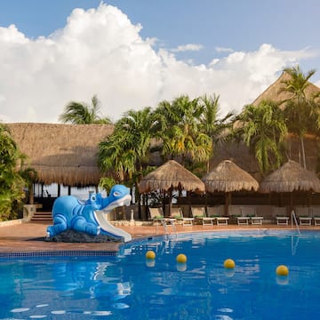 a pool with a blue dinosaur statue and palm trees