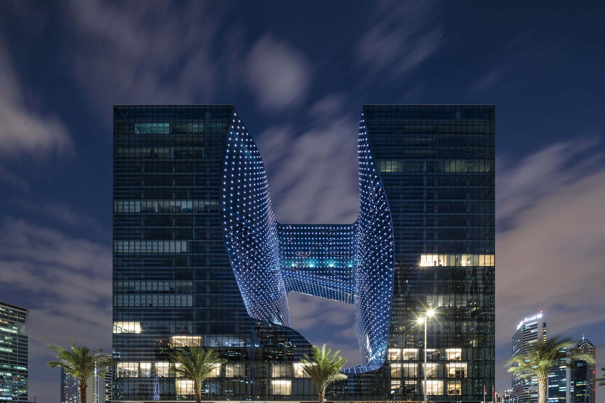 Zaha Hadid Opus building in Dubai, illuminated void at night.