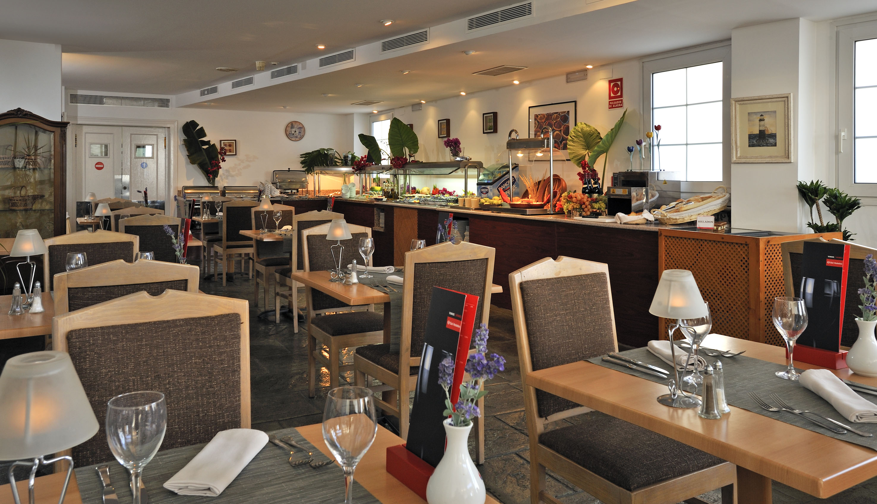 Bright restaurant interior with a hotel buffet and neatly set dining tables.
