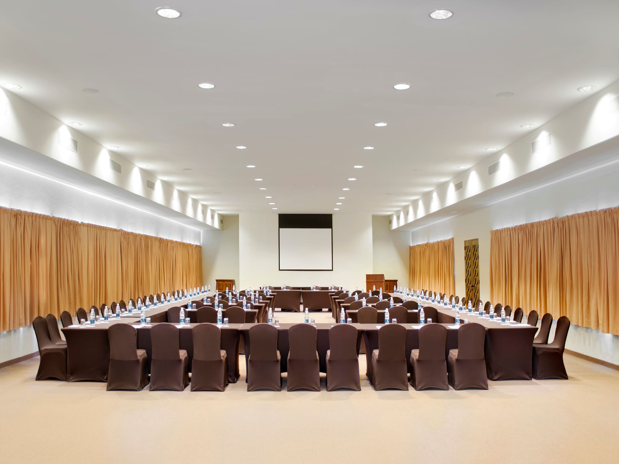 a large conference room with brown chairs and a projector screen