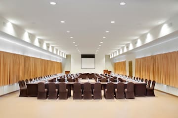 a large conference room with brown chairs and a projector screen
