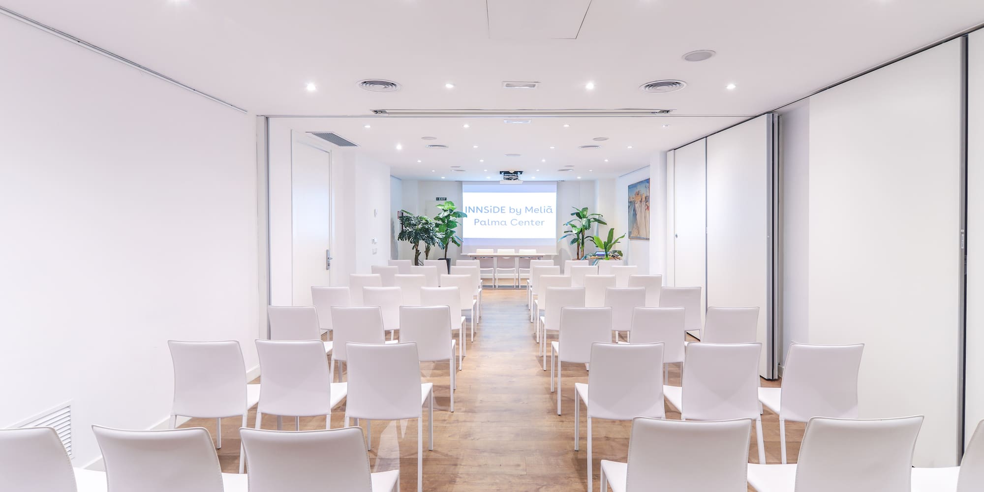 a room with white chairs and a screen