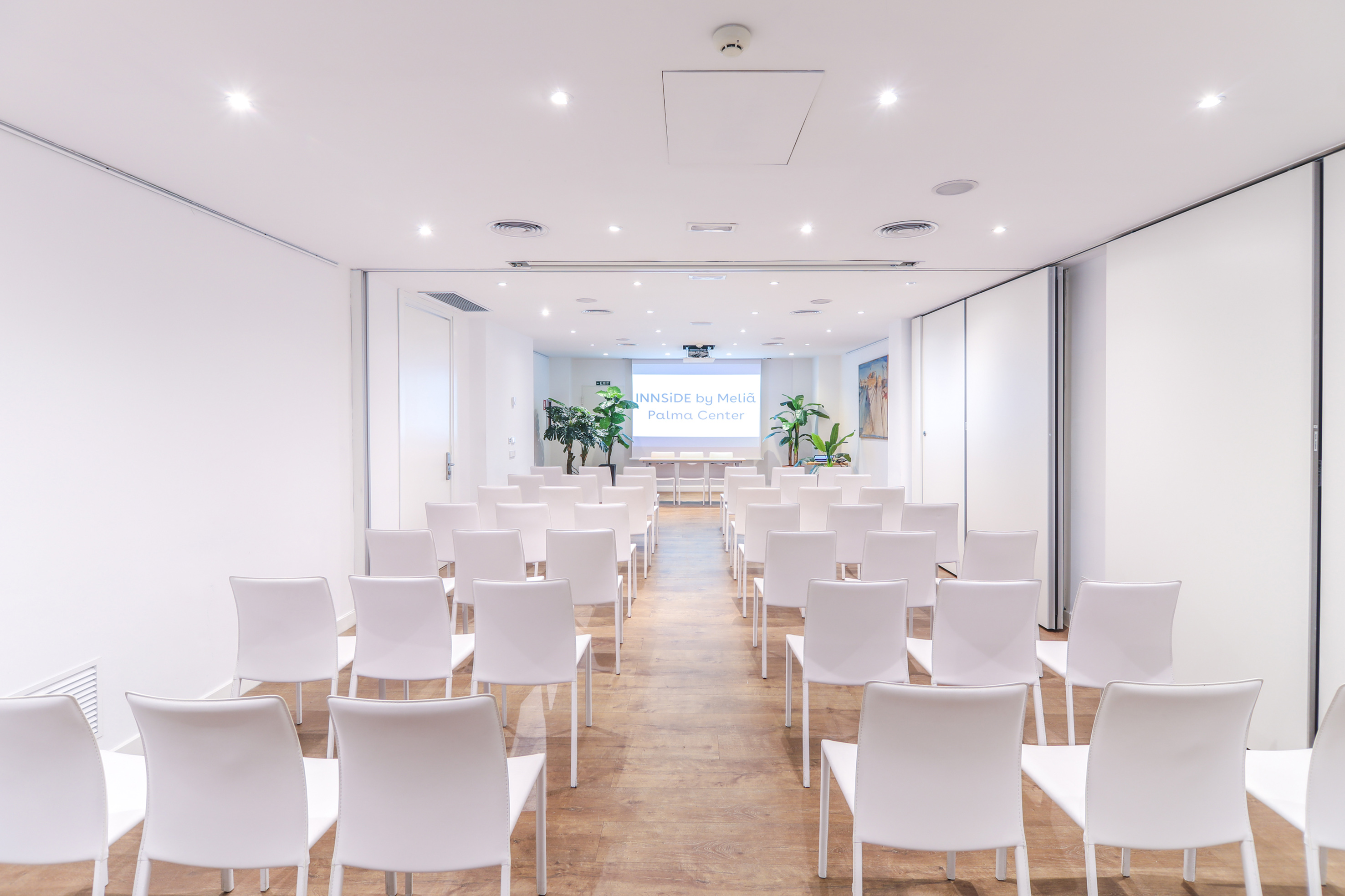 a room with white chairs and a screen