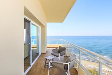 a balcony with chairs and a table overlooking the ocean