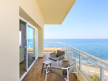 a balcony with chairs and a table overlooking the ocean