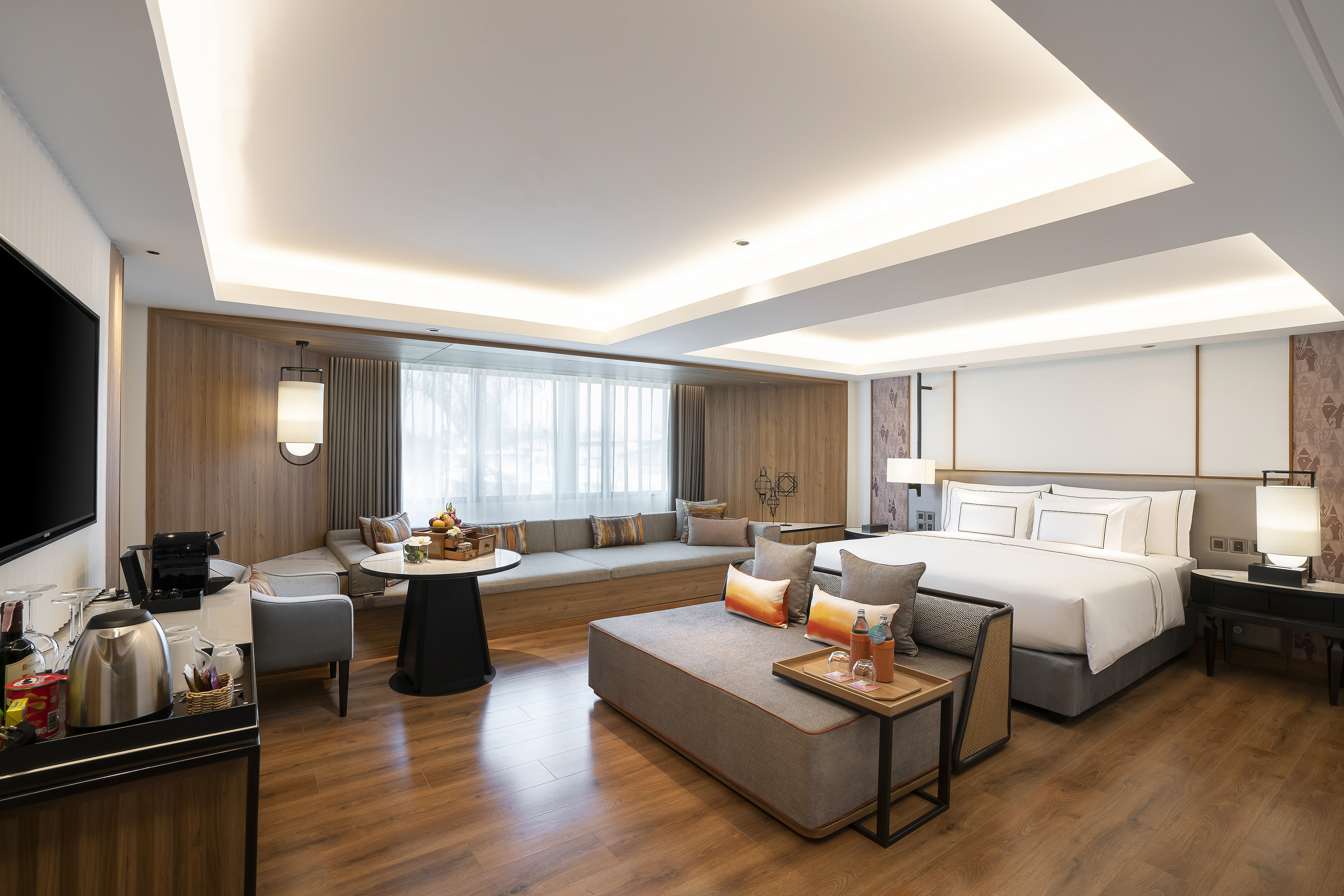 Luxury hotel suite with king bed, lounge seating, and modern wooden interior.