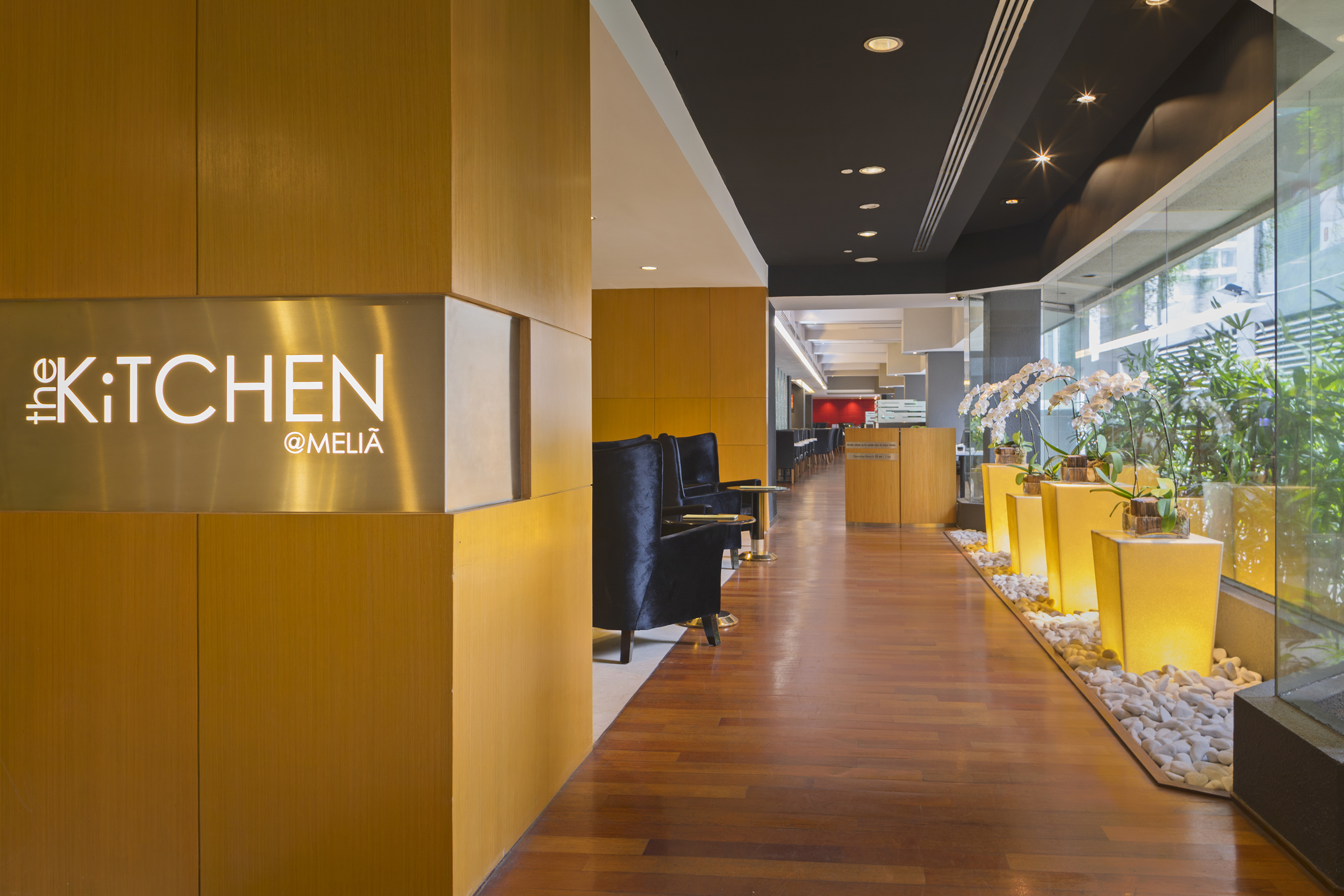 The Kitchen @Meliã restaurant entrance, modern wood interior, black chairs, orchids.