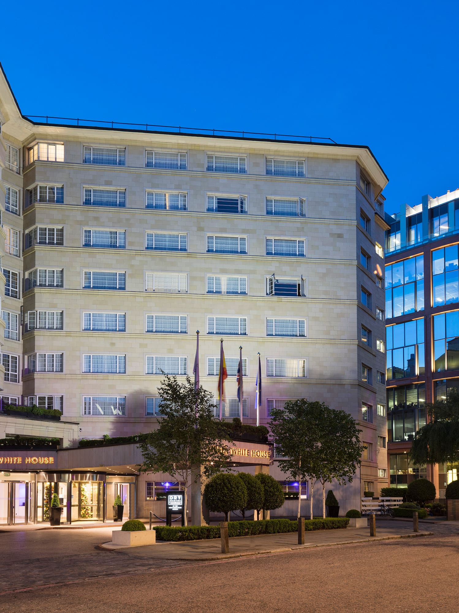 a building with many windows and a street with trees and a road