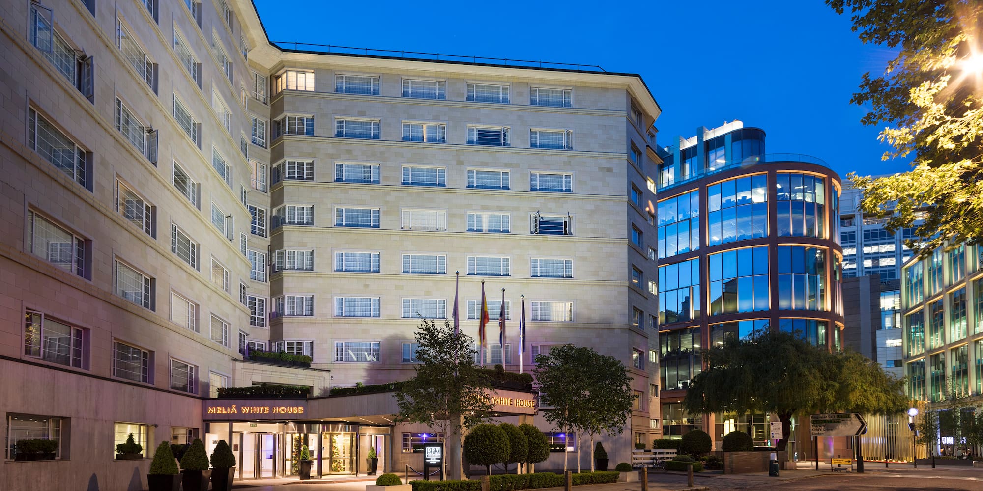 a building with many windows and a street with trees and a road