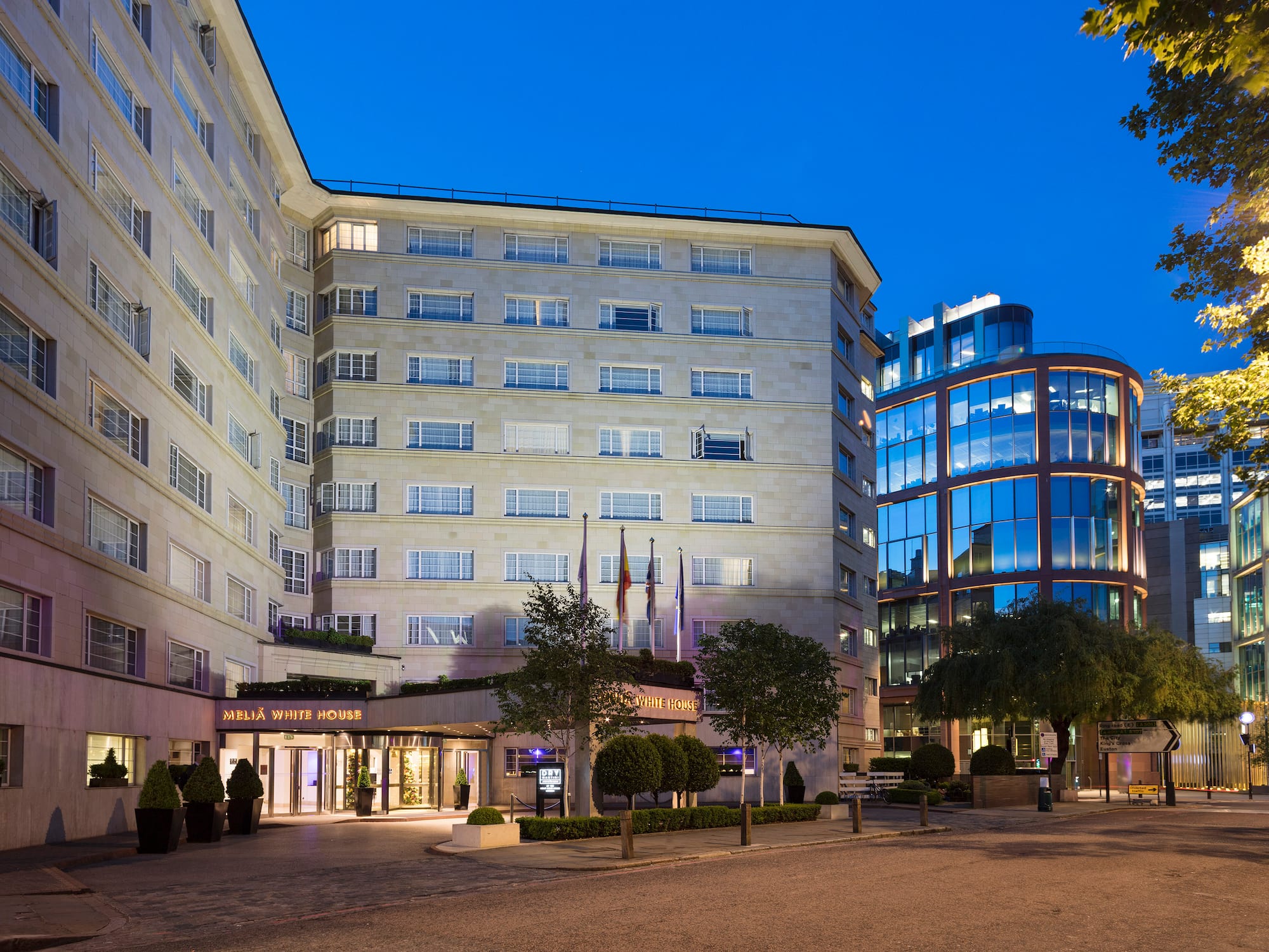 a building with many windows and a street with trees and a road