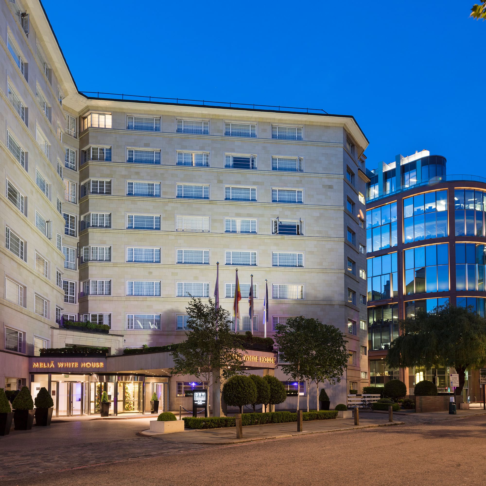 a building with many windows and a street with trees and a road