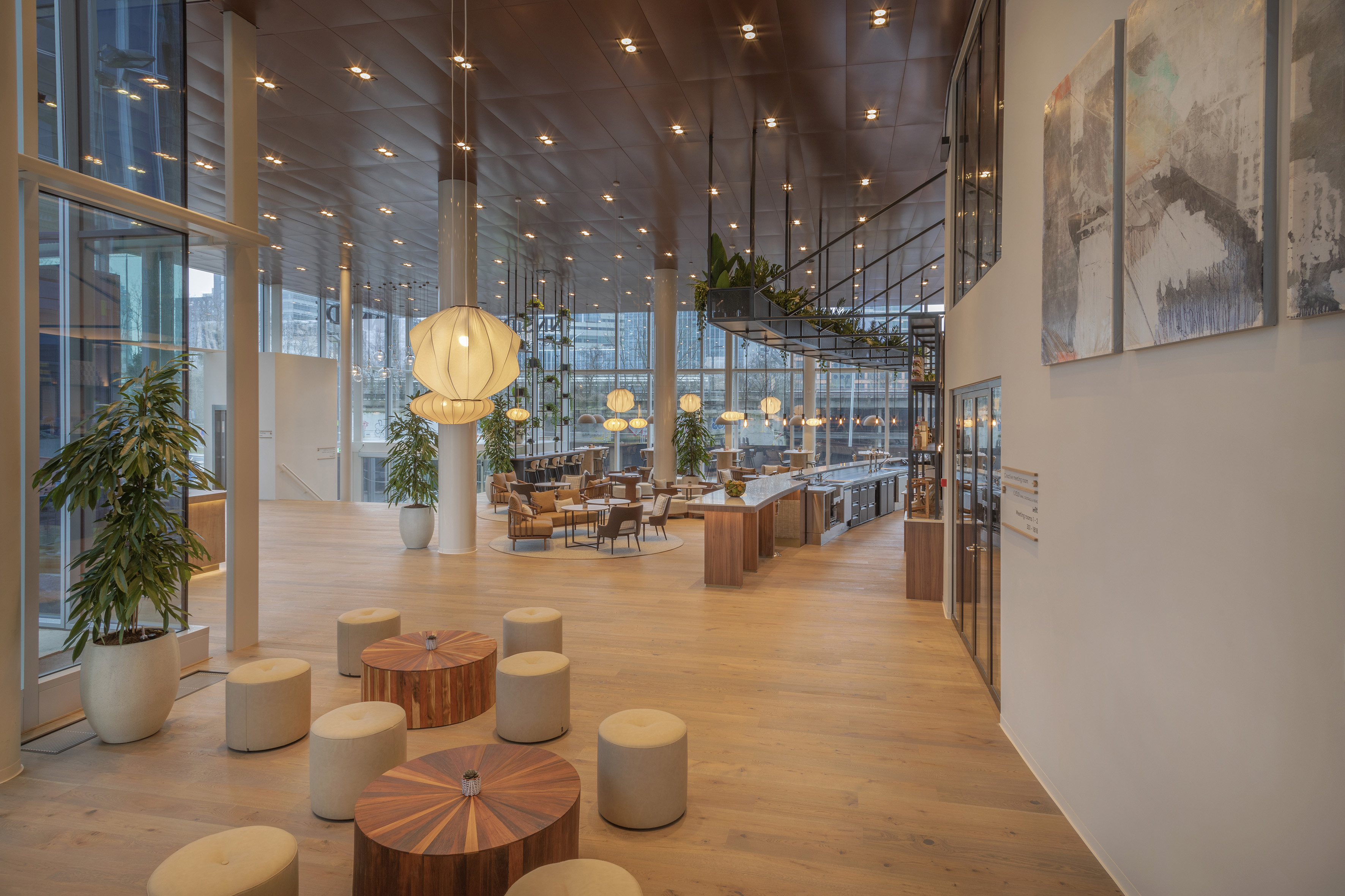 Contemporary corporate lounge with bar, wood floors, and pendant lighting.