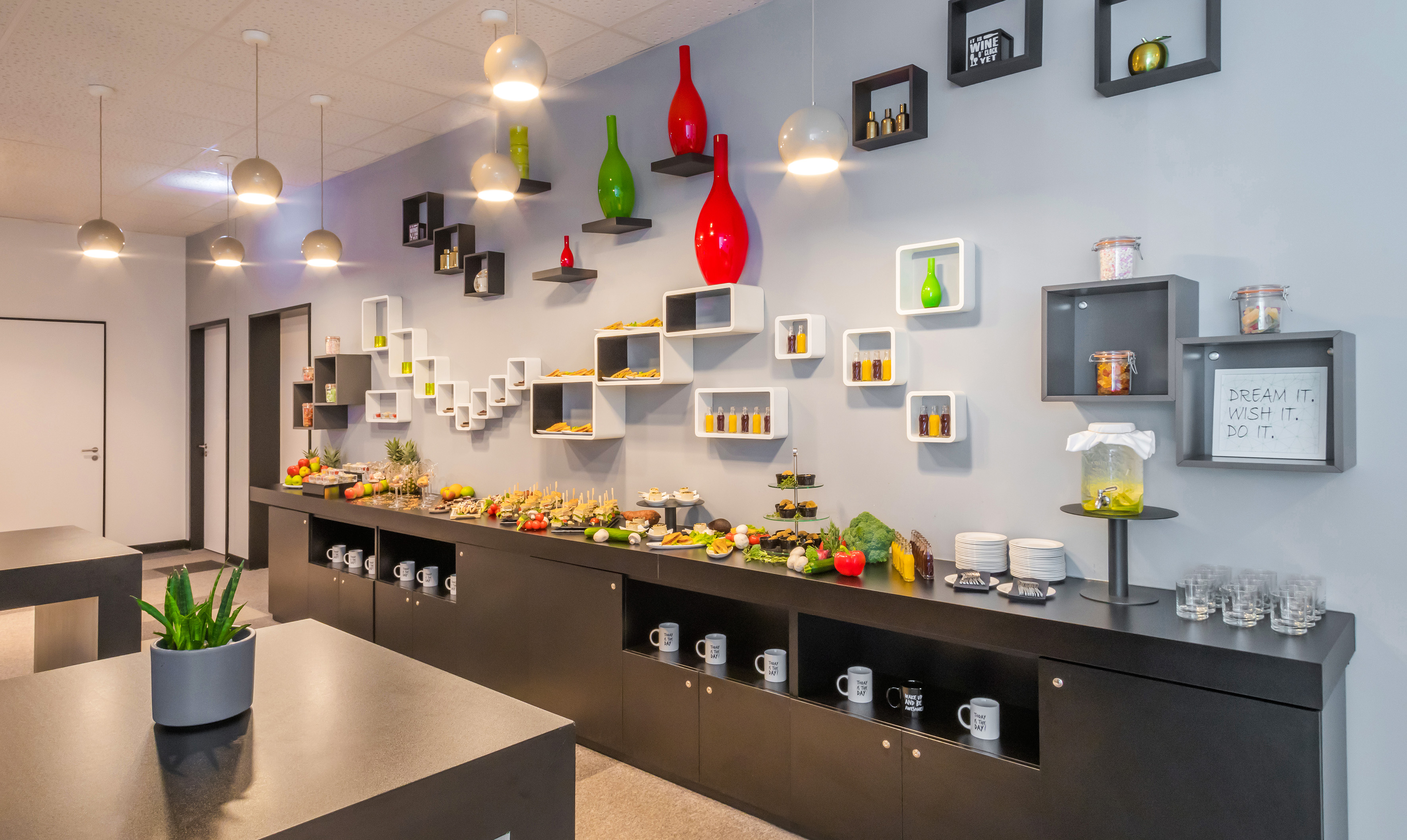 Modern office buffet with snacks, drinks, and contemporary wall decor.