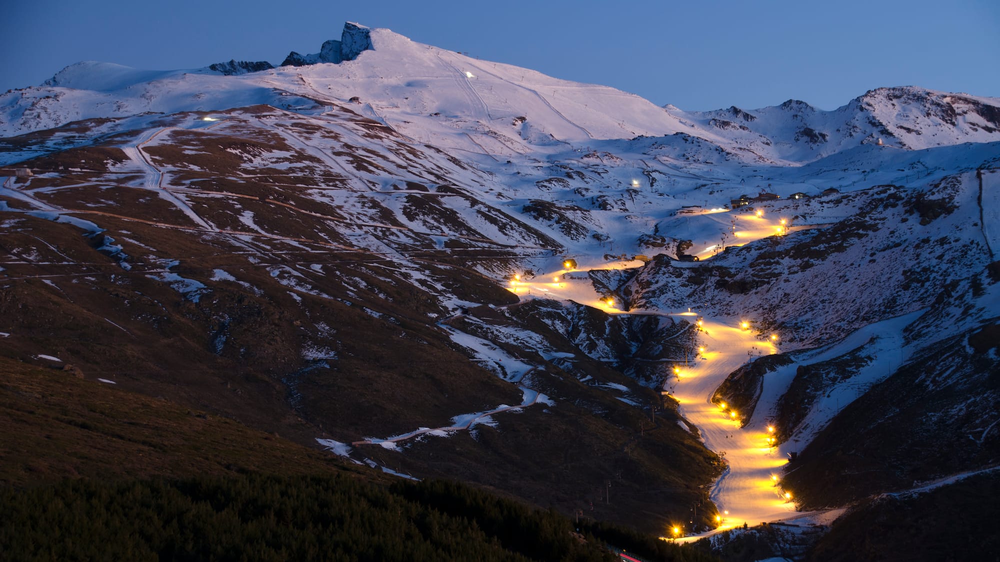 a snowy mountain with lights on it