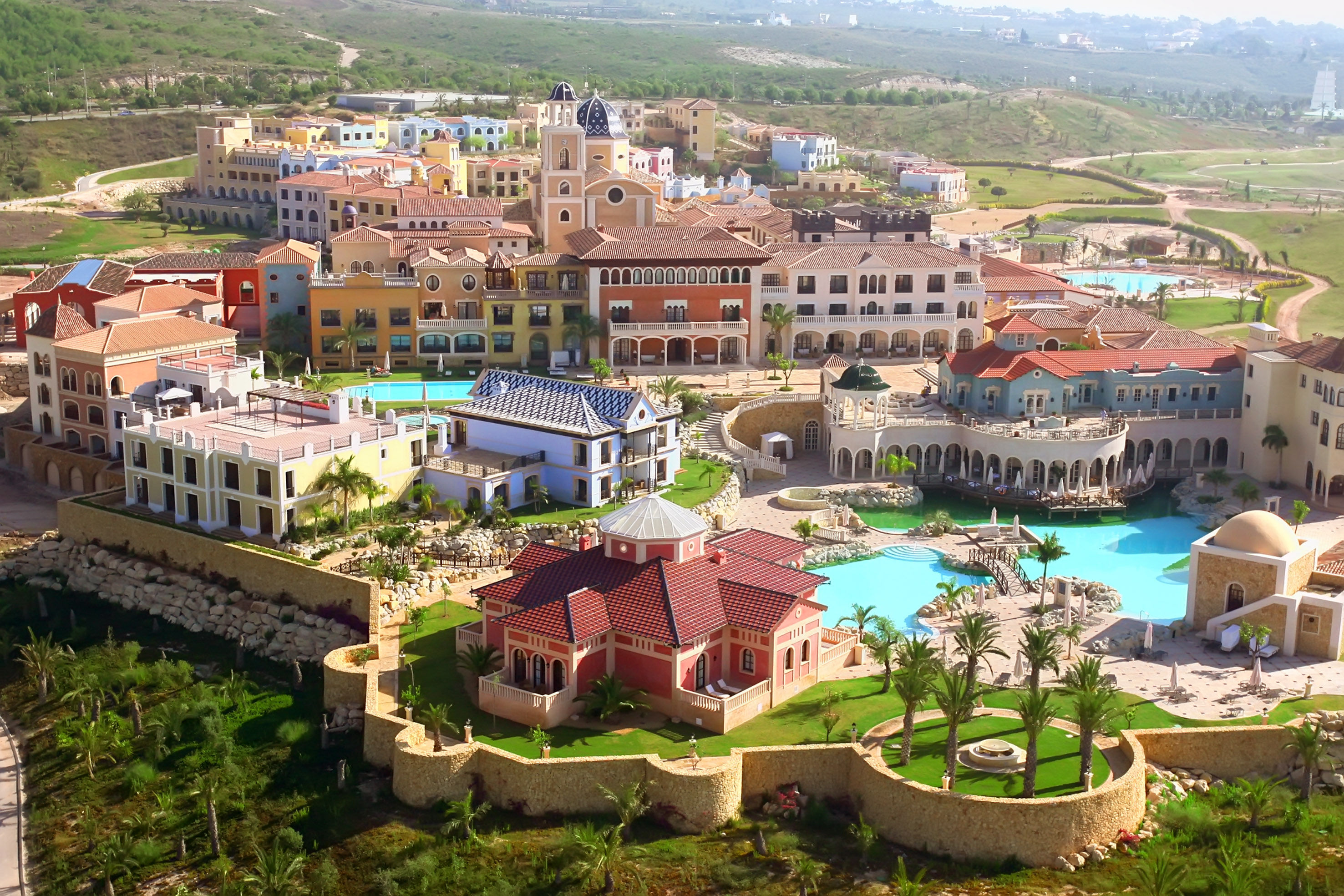 Luxury Mediterranean resort village with colorful buildings and pools.