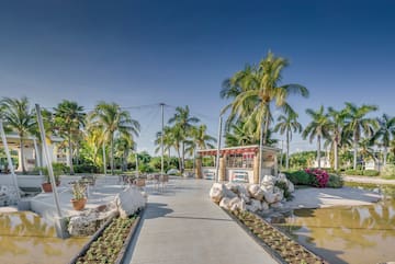 a sidewalk with tables and chairs in front of palm trees