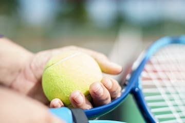 a person holding a tennis ball and racket