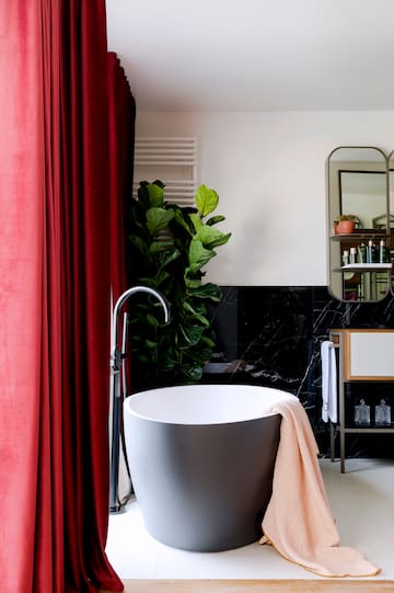 a bathroom with a tub and a red curtain