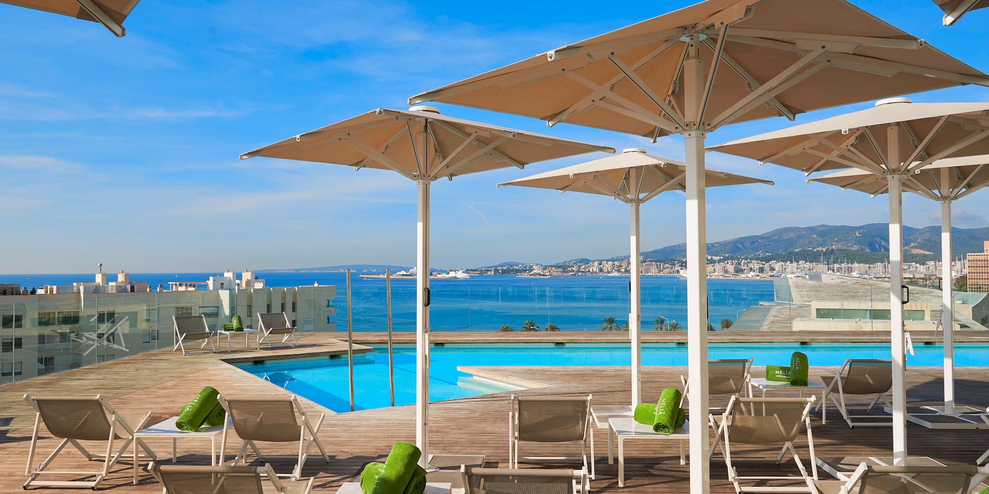 a pool with chairs and umbrellas by a building